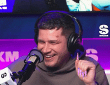 a man wearing headphones smiles in front of a siriusxm sign