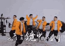 a group of men in yellow jackets are dancing in the snow with chinese writing in the background