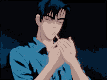a man in a blue shirt is lighting a cigarette with his hands