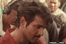 a man wearing headphones and a red shirt has the hashtag pranay_varma on the bottom