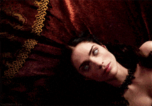 a woman with glowing eyes is laying on a bed with the words hauntedscorpio on the bottom