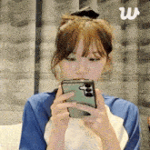 a woman in a blue shirt is holding a green cell phone in her hand .