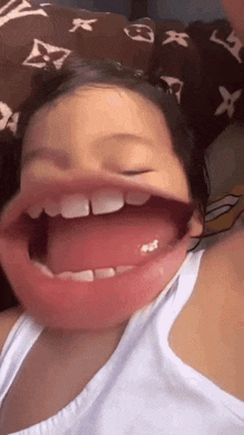 a little girl is making a funny face with her mouth open and her tongue out .