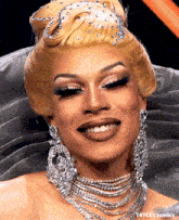a close up of a woman wearing earrings and a tiara