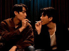 a man smoking a cigarette next to another man who is also smoking a cigarette