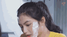 a woman is shaving her face with a razor and foam .