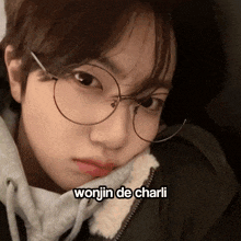 a close up of a person wearing glasses with the name wonjin de charli written below them