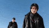 a man with a scarf around his neck is standing in front of a blue sky