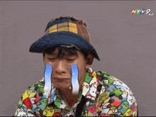 a man wearing a hat and a shirt with birds on it is crying while watching htv
