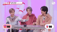 three young men are sitting at a table with a heart that says 90