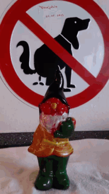a statue of a gnome standing in front of a no dogs sign