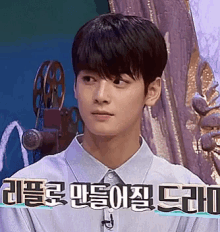 a young man in a blue shirt is sitting in front of a microphone in front of a picture frame .