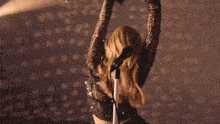 a woman singing into a microphone with her arms outstretched