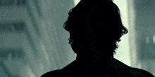 a silhouette of a man 's back is shown in a dark room