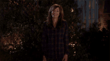 a woman wearing a plaid shirt is waving her hand