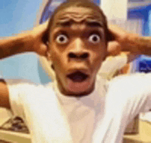 a man in a white shirt is making a surprised face while holding his hands to his ears .