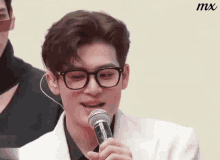 a man wearing glasses is holding a microphone in his mouth