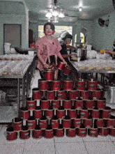a woman in a pink dress is standing in front of a stack of red cans that say ' ikan mas ' on them