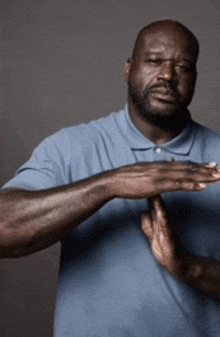 a man in a blue shirt is making a stop gesture with his hands