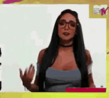 a woman with long hair and glasses is waving her hand
