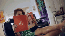 a woman sits in a chair reading a book called icon