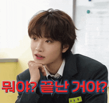 a man in a suit and tie is sitting in front of a sign that says ' ? ' on it