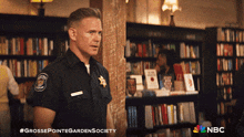 a man in a police uniform is standing in a bookstore with a nbc logo on the bottom right