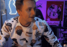 a man wearing a white sweater with a vodka cola poster in the background