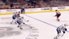 a hockey game is being played in front of a sign that says ' toronto maple leafs ' on it