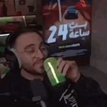 a man wearing headphones is drinking from a green cup .