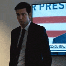 a man in a suit and tie is standing in front of a tv screen that says ' r pres ' on it