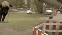 a woman is swinging on a swing in a park next to a fence .