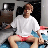 a young man is sitting on a bed with his legs crossed .