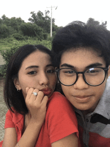a boy and a girl are posing for a picture and the girl is wearing a ring