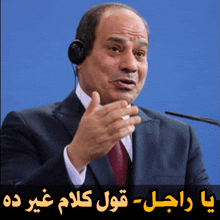 a man in a suit and tie speaking into a microphone with arabic writing below him