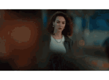 a woman wearing a black leather jacket and a white shirt is walking down a street .