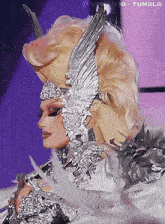 a woman is wearing a costume with feathers and a helmet that has wings on it