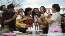 a group of people are celebrating a birthday with a cake with candles dripping from it