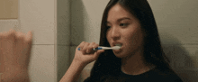 a young woman is brushing her teeth in front of a mirror
