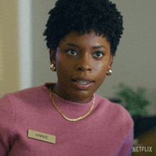 a woman wearing a pink sweater with a name tag that says annie