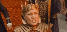 a woman wearing a crown and armor is sitting in a chair .