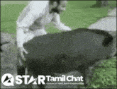 a man standing next to a large black animal with a star tamil chat logo