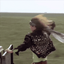 a woman wearing a headband and a scarf is running across a field