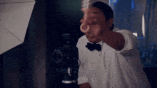 a man in a white shirt and bow tie is pointing at a camera