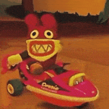 a stuffed animal is riding a pink toy car on a tiled floor .