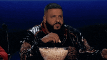 a man sitting at a table with a bowl of popcorn in front of him