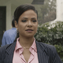 a woman wearing a pink shirt and a striped jacket