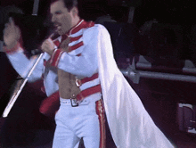 a man singing into a microphone with a white cape