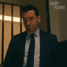 a man in a suit and tie is standing in front of a door that says saint-pierre
