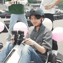 a young man wearing a helmet is sitting on a go kart with balloons in the background